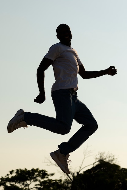 Free Photo full shot man silhouette jumping at sunset