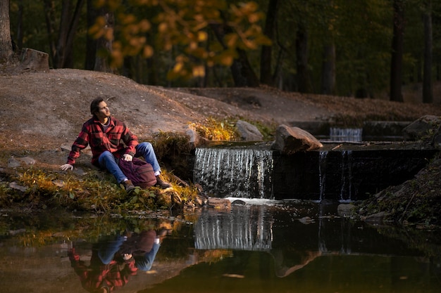 Free Photo full shot man sitting by the river