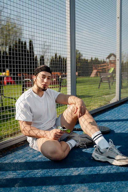 Free photo full shot man sitting in paddle tennis court