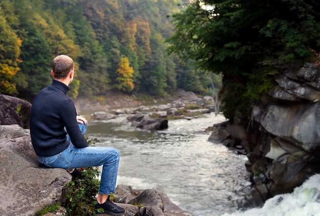 Free photo full shot man sitting on rock