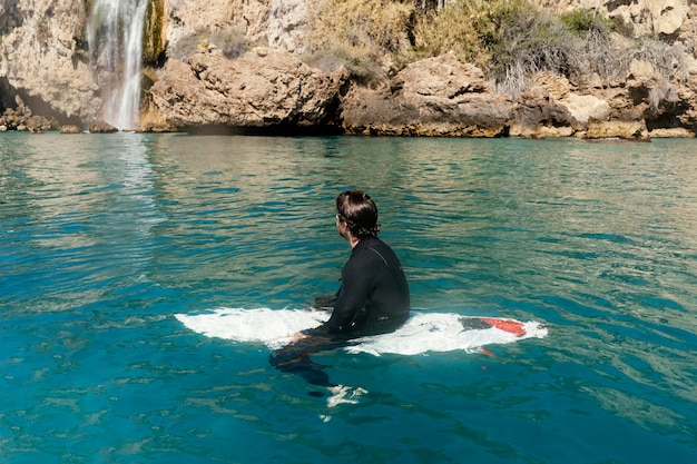 Full shot man sitting on surfboard