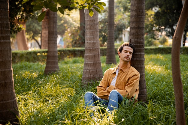 Free photo full shot man sleeping near tree