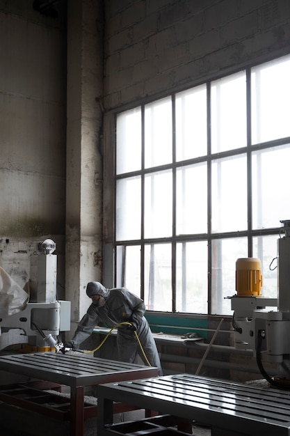 Free photo full shot man spraying powder paint from a gun