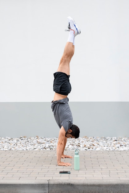 Free photo full shot man standing on hands