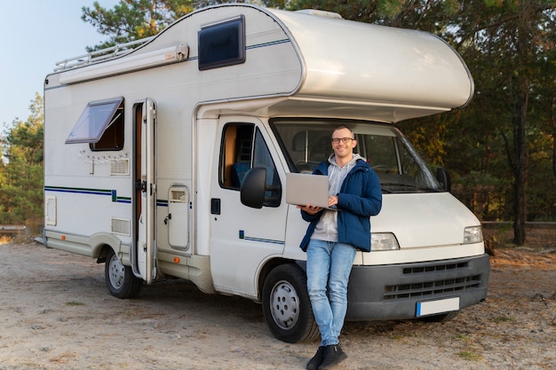 Full shot man standing near campervan