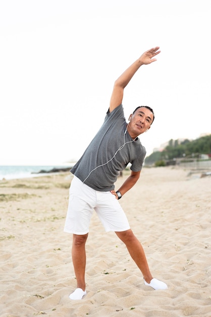 Full shot man stretching on beach