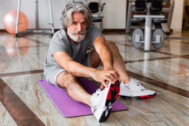 Full shot man stretching at gym