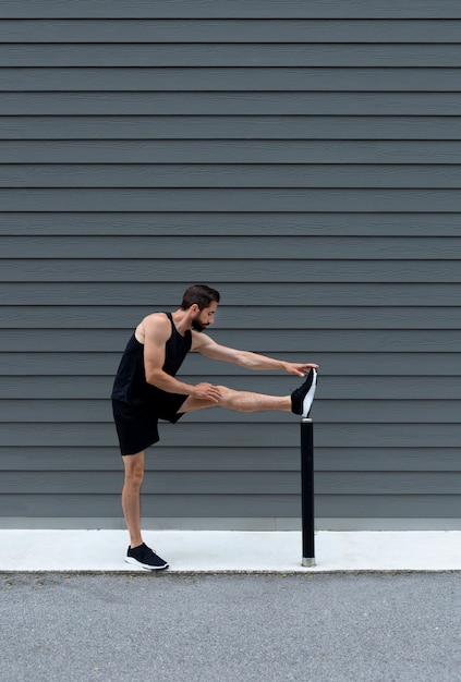 Full shot man stretching leg