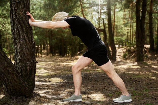 Full shot man stretching with tree