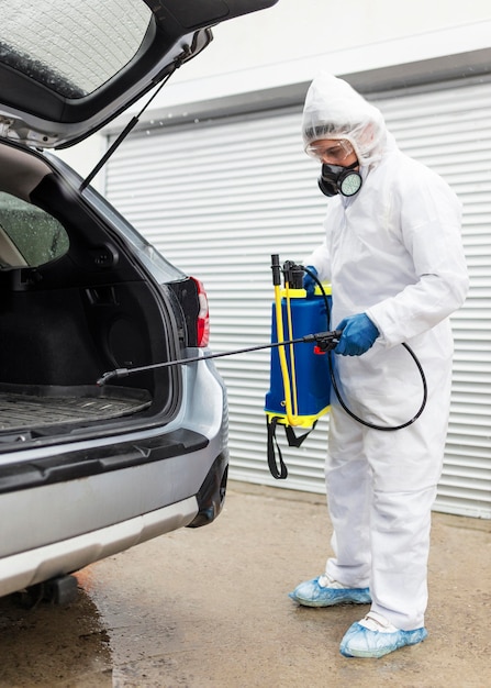 Full shot man in suit disinfecting car