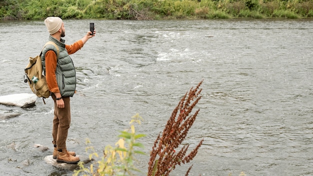 Full shot man taking photos of river