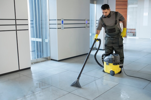 Full shot man vacuuming office floor