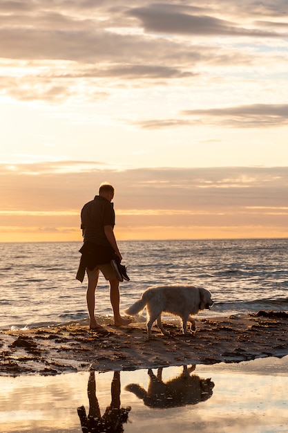 Full shot man with cute dog on beach