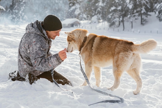 Free photo full shot man with dog in snow