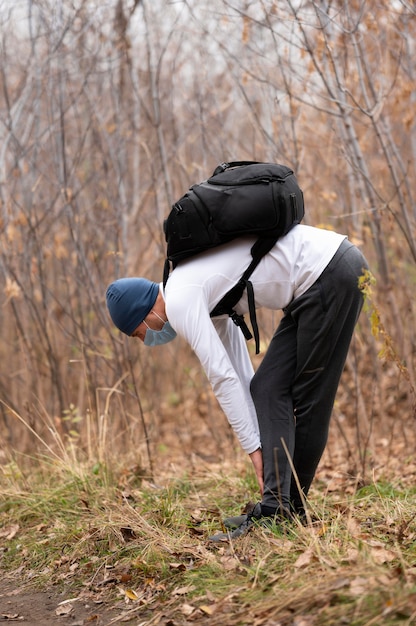 Free photo full shot man with face mask and backpack in the woods