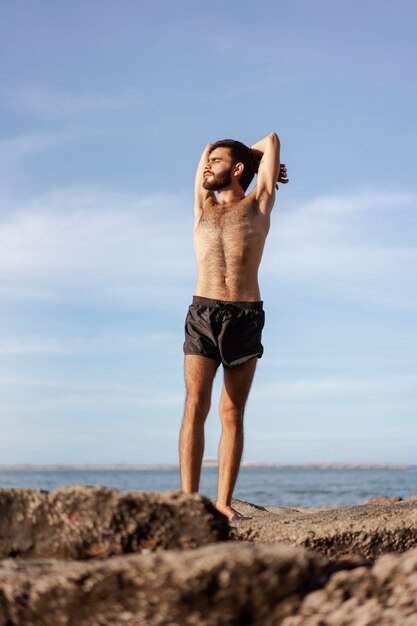 Full shot man with hairy chest at seaside