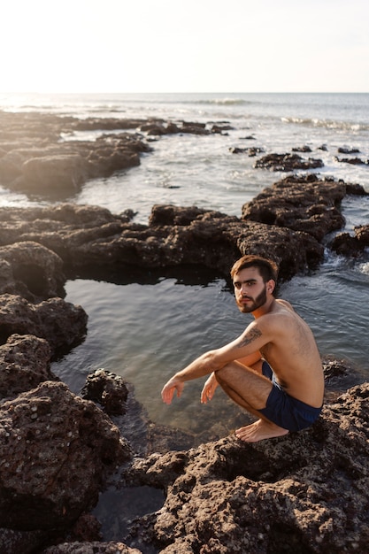 Full shot man with hairy chest at seaside