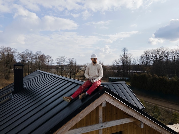 Free photo full shot man with helmet sitting on roof