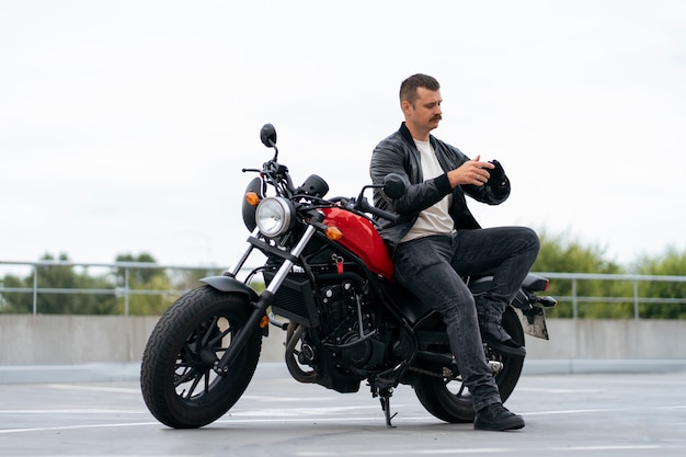 Full shot man with motorbike outdoors