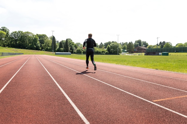 Full shot man with prosthesis running  outdoors