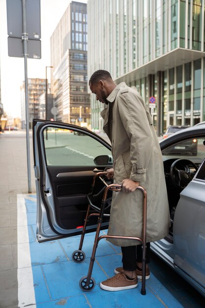 Full shot man with walking frame and car