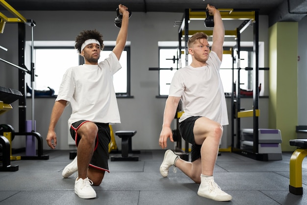 Full shot men exercising with kettlebells