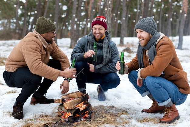 Free photo full shot men sitting by the fire