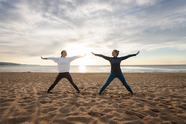 Full shot mother and daughter doing yoga