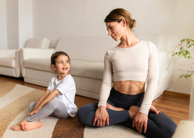 Full shot mother and girl sitting on floor