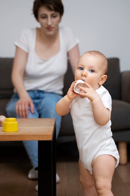 Full shot mother watching baby standing