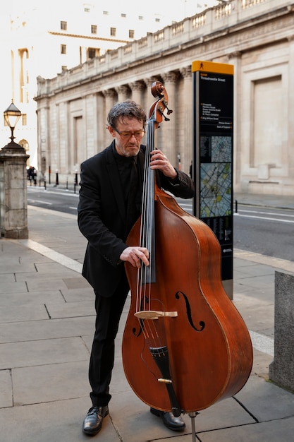 Free Photo full shot musician playing the double bass outdoors