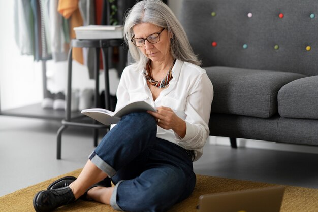 Full shot old woman reading on floor