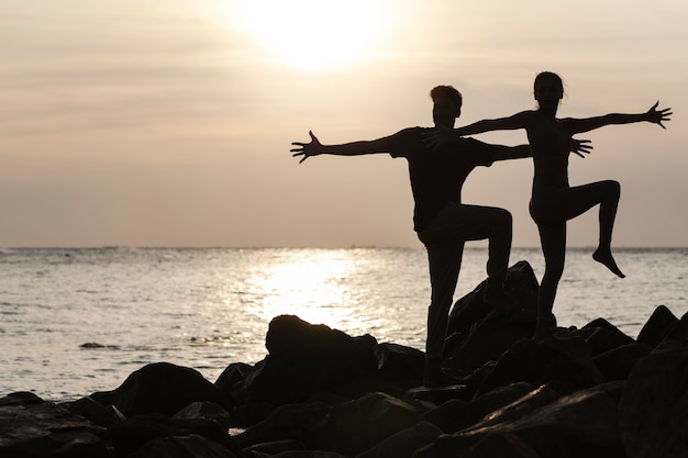 Free photo full shot people doing yoga at sunset