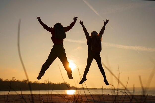 Full shot people jumping at sunset