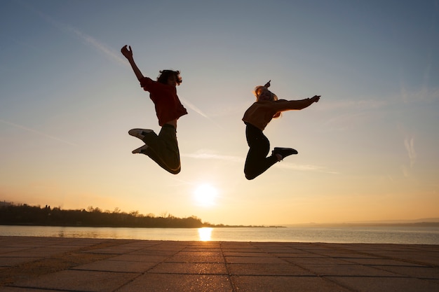 Full shot people jumping at sunset