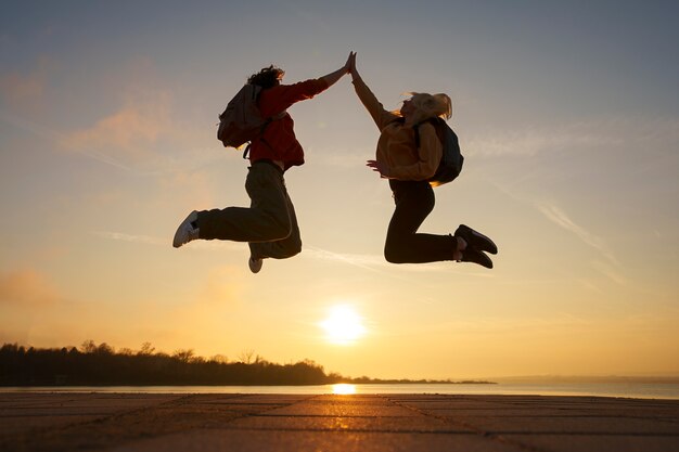 Full shot people jumping at sunset