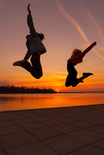 Full shot people jumping at sunset