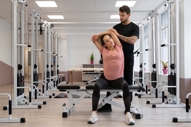 Full shot physiotherapist helping woman