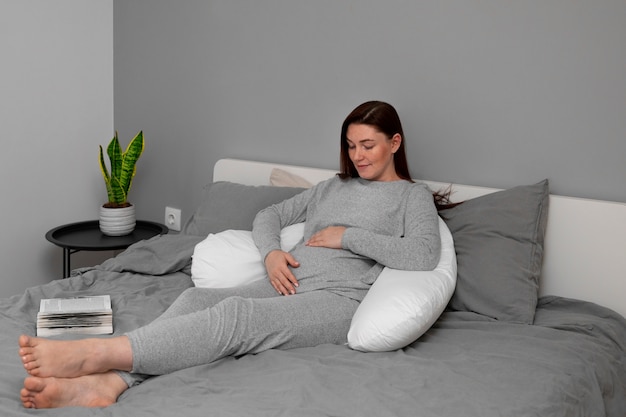 Full shot pregnant woman sitting at home