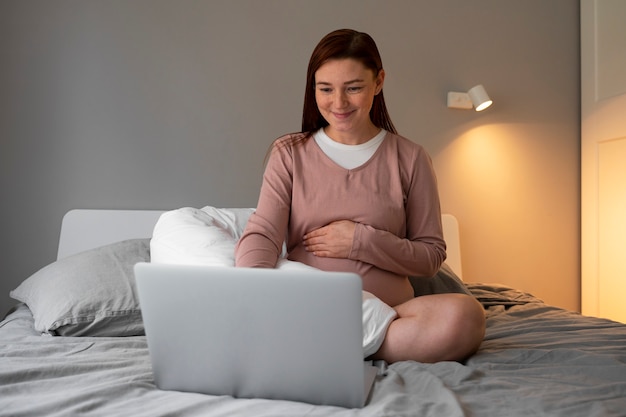 Full shot pregnant woman sitting at home