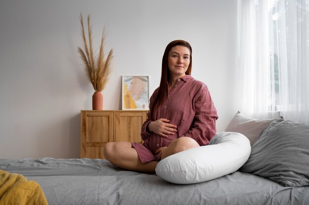 Full shot pregnant woman sitting at home