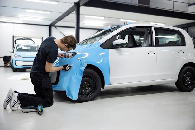 Full shot professional wrapping car with blue cover