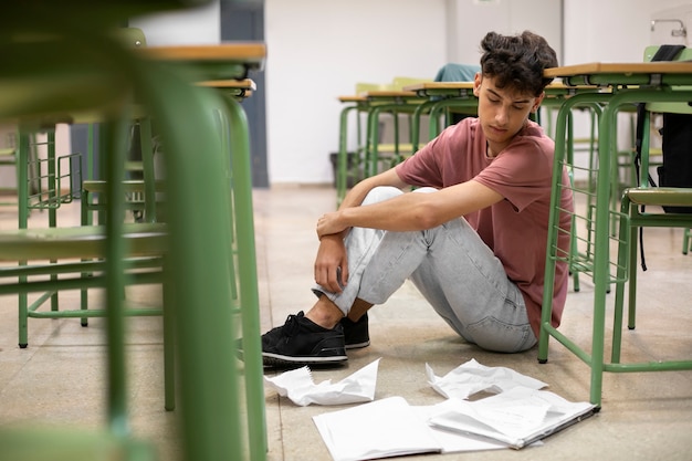 Full shot sad boy in classroom