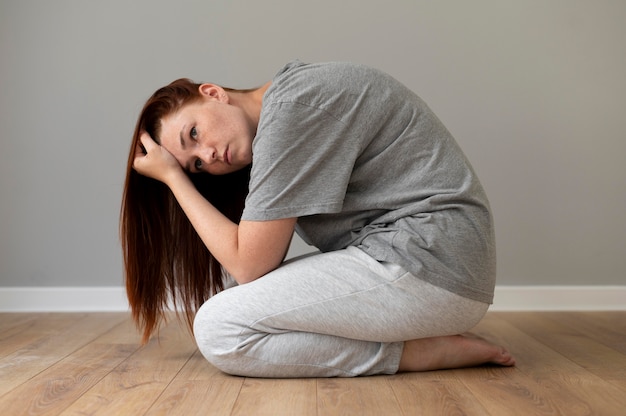 Free photo full shot sad woman laying on floor