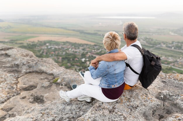 Full shot senior couple sitting on cliff