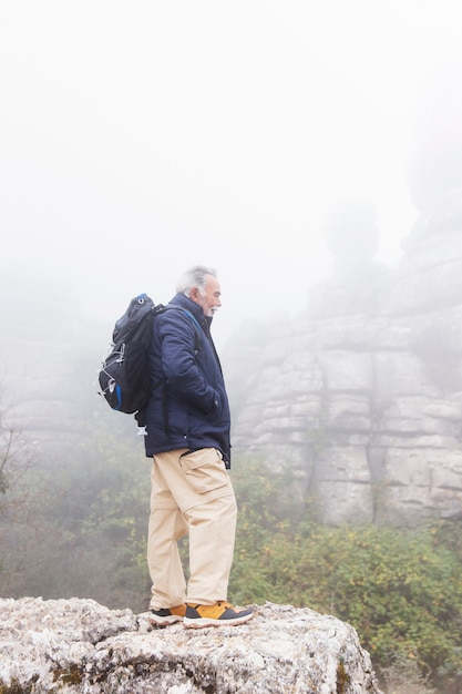 Free photo full shot senior man standing on rock