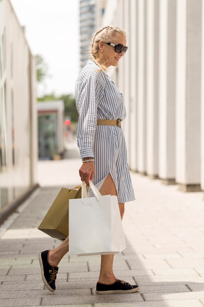 Free Photo full shot senior woman carrying shopping bags