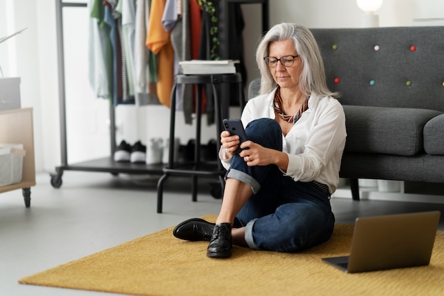 Full shot senior woman holding smartphone