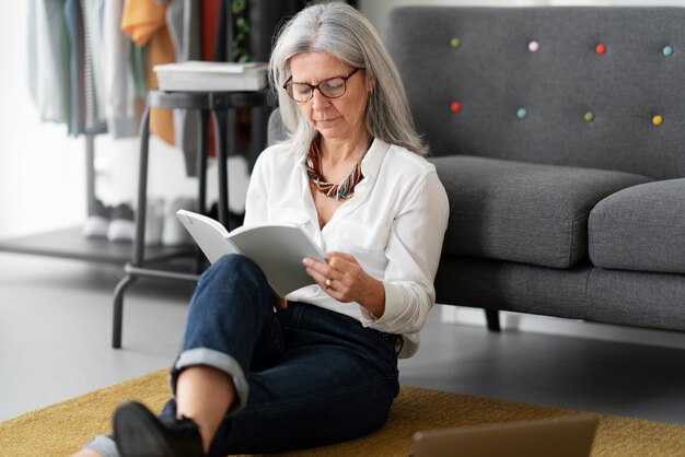 Full shot senior woman reading on floor