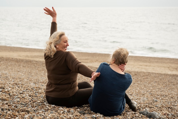 Full shot senior women sitting on beach